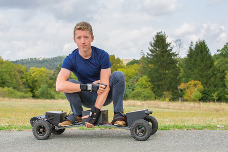 Young caucasian man drives electrical mountainboard on road in natureの写真素材