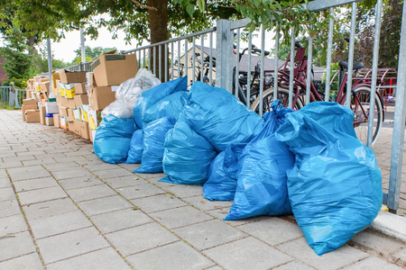Blue garbage bags and boxes with waste are standing on dutch footpathの写真素材