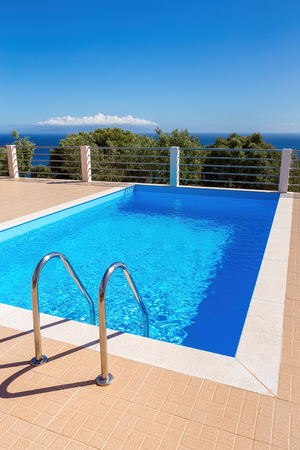 Water in blue greek swimming pool at sea with sky during summer seasonの写真素材