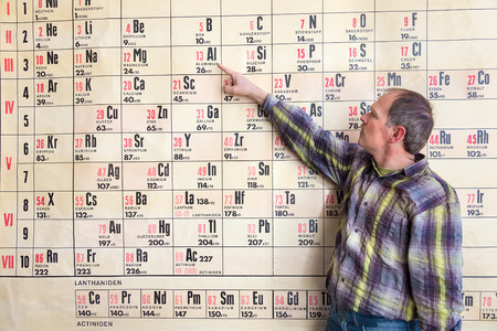 Chemistry teacher points at periodic table on wall chart hanging in high schoolの素材 [FY310121767610]