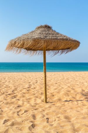 One thatched beach parasol at blue sea in portugalの写真素材