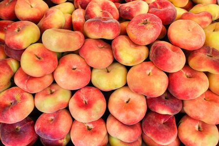 Multiple colorful fresh flat peaches for sale at market