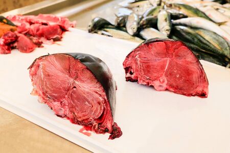 Parts of chopped red tuna fishes on the counter at marketの写真素材