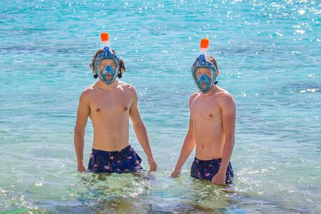 Two young caucasian men wearing snorkel masks in seaの写真素材