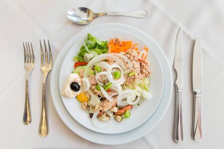Plate with fresh salad on set table with garnishの写真素材
