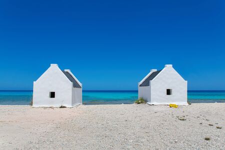 Two white slave houses on beach with blue sea on island Bonaireの写真素材