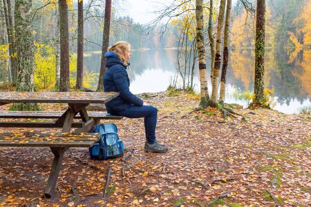 Woman sitting at picnic table during autumn season in Finlandの写真素材