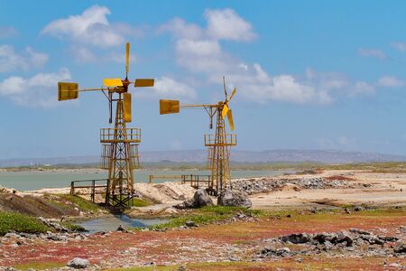 Two yellow windmills for salt extraction near water on island Bonaireの写真素材