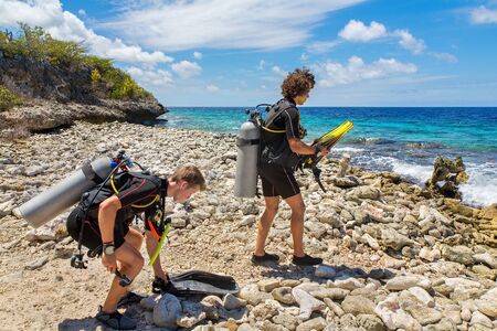 Two young caucasian divers on the beach walking to the seaの写真素材