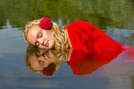 Portrait of young caucasian woman with reflection in natural waterの写真素材