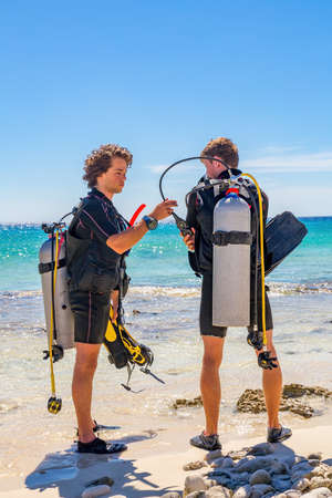 Two young caucasian divers checking diving equipment at coast of island Bonaireの写真素材