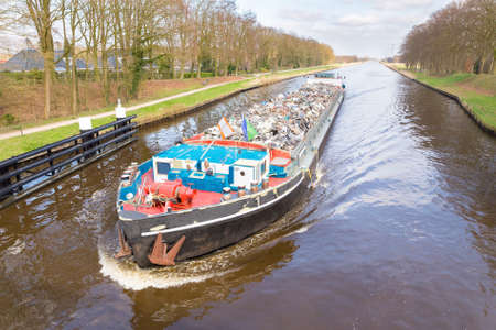 Dutch cargo ship sailing with recyclable metal on channelの写真素材