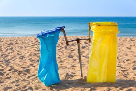 Empty garbage bags at sandy portuguese beach with blue seaの写真素材