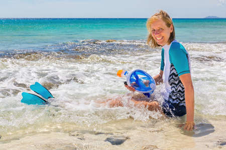 Caucasian woman sitting in sea water with snorkel mask and finsの写真素材