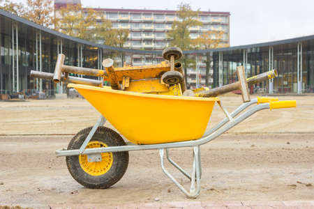 Yellow wheelbarrow with stone cutter on new square pavementの写真素材