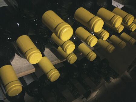 Wine bottles with yellow cap in rack at cellar