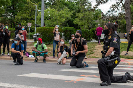 Bethesda, Md. - June 2, 2020: A Montgomery County, Md. police officer kneels with protesters who had gathered to demand police reform after the killing by police of Minneapolis resident George Floyd.のeditorial素材