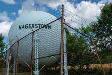A water tower stands behind a delapidated barbed wire fence in Hagerstown, Washington County, Maryland.の写真素材