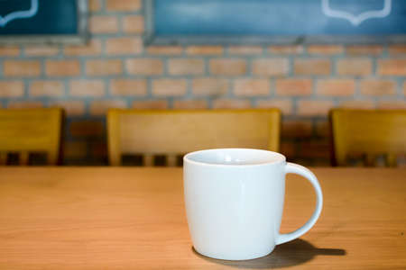 Cup Of Coffee on the Wooden Table on Blur Backgroupnd, Bricks and Blackboards.の写真素材