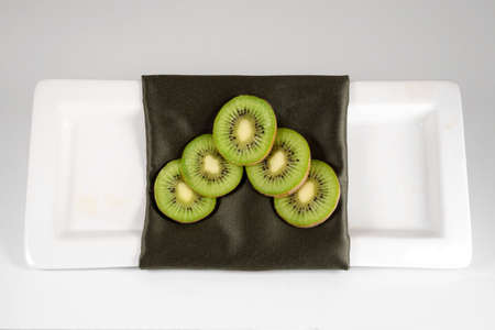 An arrangement of kiwi on a green decorative napkin on a white plate with a white background.の写真素材