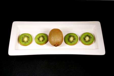 Kiwi arranged on a white plate with a black background.の写真素材