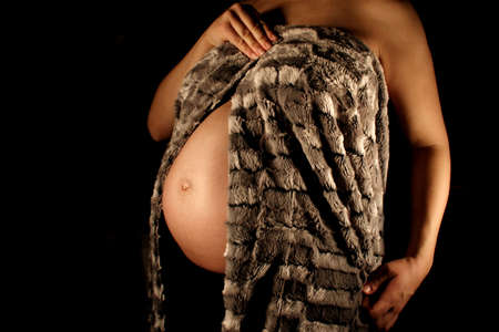 A pregnant woman wrapped in a faux-fur blanket.の写真素材