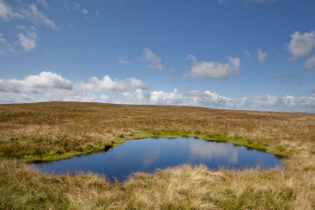 Lake on Wild Boar Fell with blue sky and a foreground lake  の写真素材
