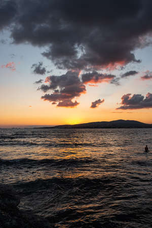 A bright sea sunset smoothly leaves the Bay, going behind the mountains of the resort city of Gelendzhik. Colorful summer landscape, beautiful clouds, comfortable rest on the Black sea coastの写真素材