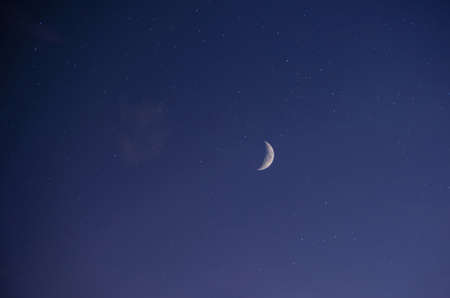 Night landscape, dark blue starry sky, view of the bright moon (Crescent) in cloudless weather. Photo on a long-focus lens with layers applied. The city resort of Gelendzhik, Russiaの写真素材