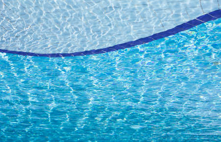 Background of clear blue water with sun reflections in an outdoor swimming pool の写真素材
