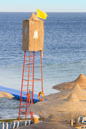 A wicker lifeguard watchtower or lookout tower and yellow flag on a beach の写真素材