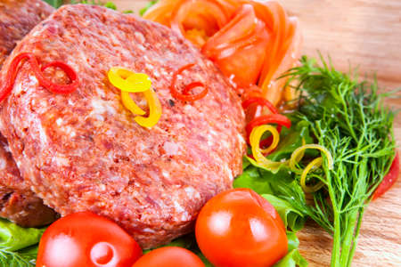 Fresh raw burger cutlet with herbs pepper and tomatoesの写真素材