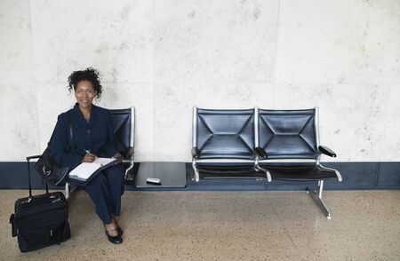 Portrait of a young businesswoman sitting in an airport with luggageの写真素材