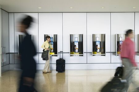 Side profile of a businesswoman using a payphone in an airport