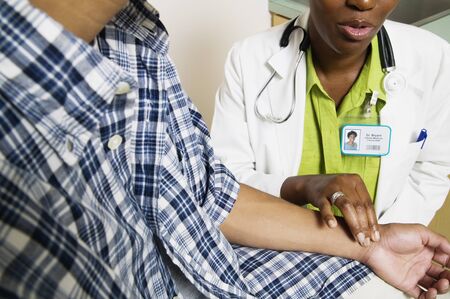 Female doctor taking a teenage boy's pulseの写真素材