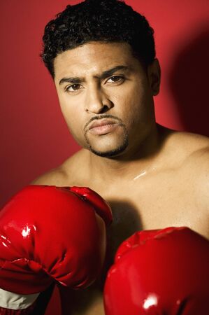 Young male boxer wearing boxing gloves looking at cameraの写真素材