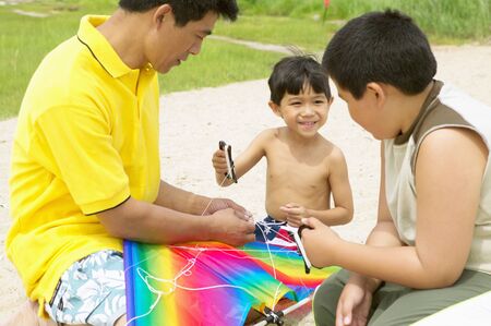 Father and his two sons at the beachの写真素材