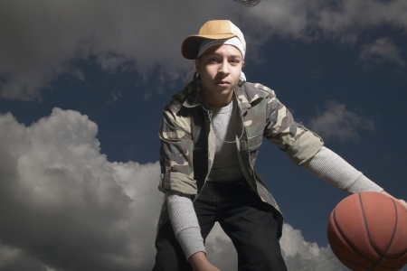 Low angle view of a young man playing with basketballの写真素材