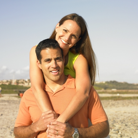 Portrait of a mid adult woman riding piggyback on a mid adult manの写真素材