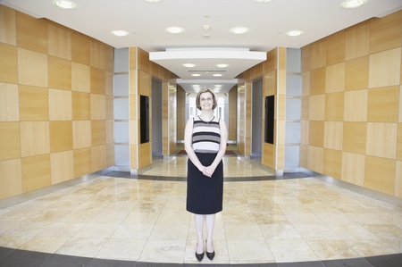 Portrait of a businesswoman standing in a corridor with her hands claspedの写真素材
