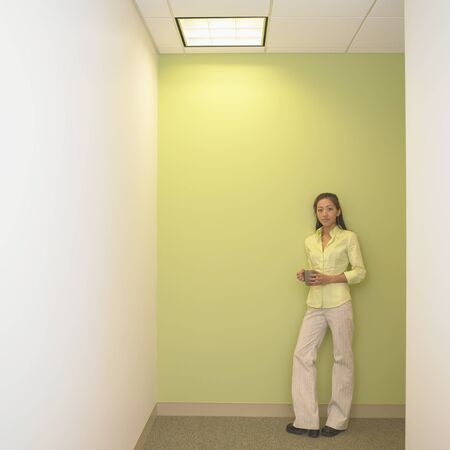 Portrait of a businesswoman holding a coffee cup in a corridorの写真素材
