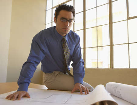 Portrait of a businessman sitting on a table with blueprints
