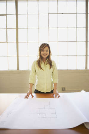 Portrait of a businesswoman with blueprints on a table in an office