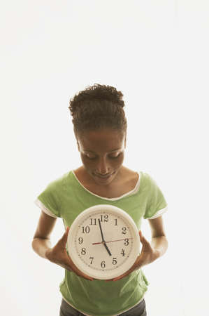 Young woman holding a clockの写真素材