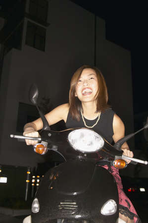 Young woman smiling sitting on a scooter