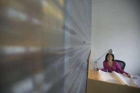 Businesswoman looking at blueprints in an office