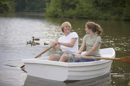 Teen couple rowing boatの写真素材