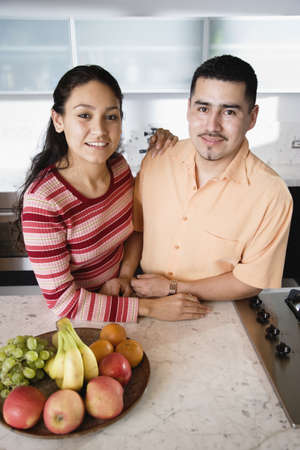 Young couple in kitchen looking at cameraの写真素材