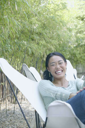 Young woman sitting on a chair outdoors smiling