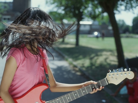 Teenager tossing hair while playing guitarの写真素材